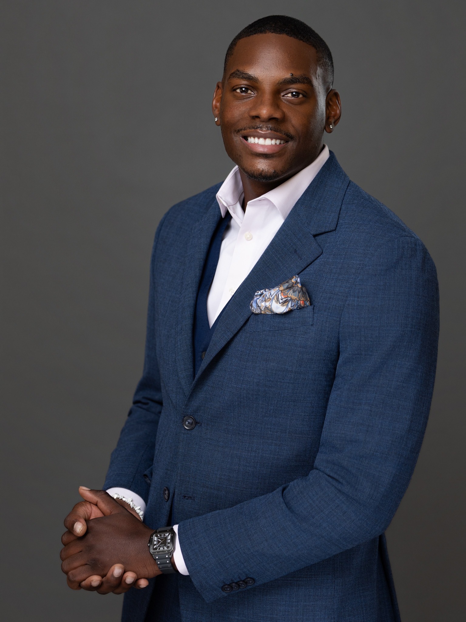 Professional studio portrait of a smiling man in a navy suit